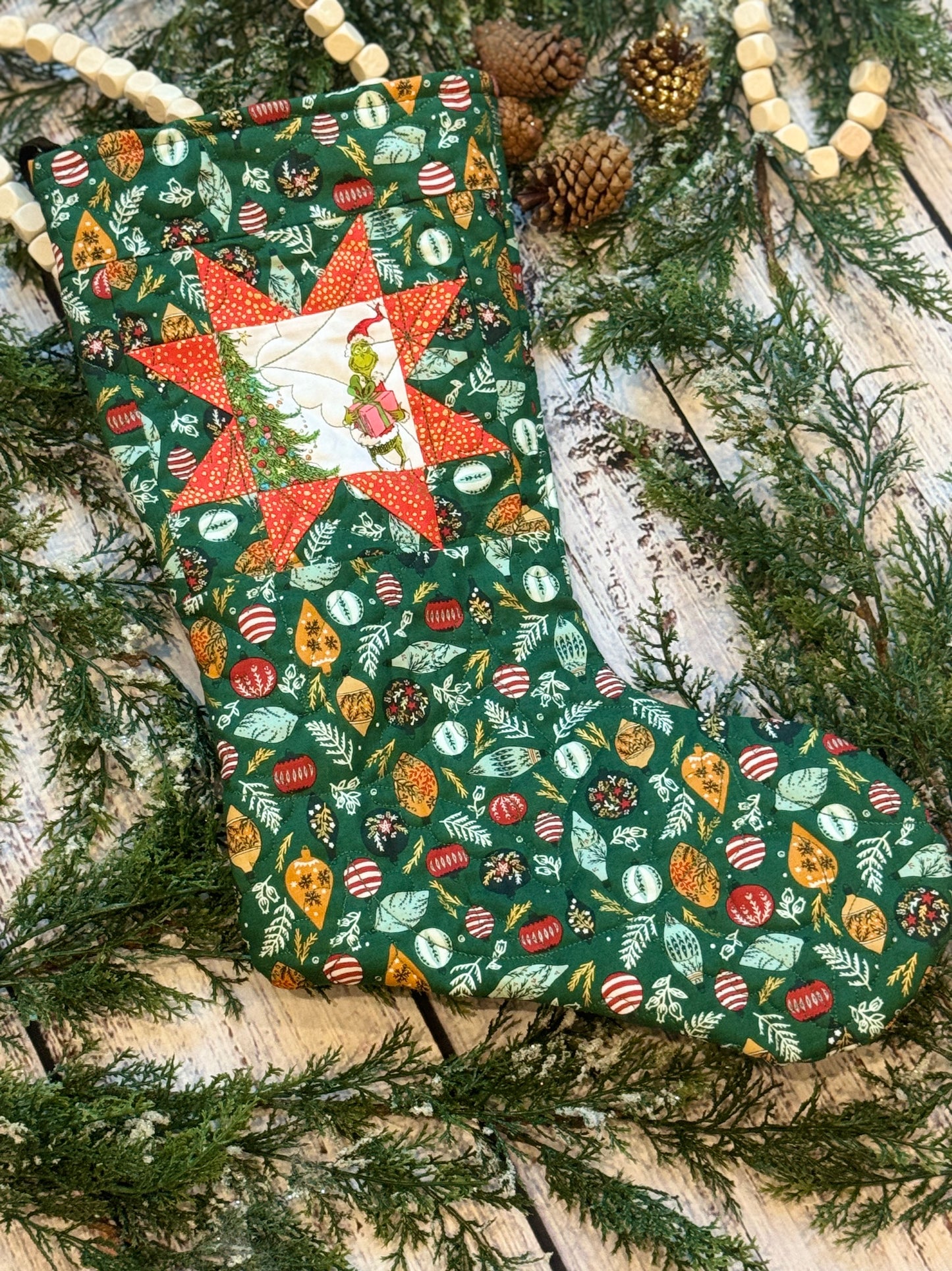 The Grinch Stocking holding Pink Present on Green Ornaments